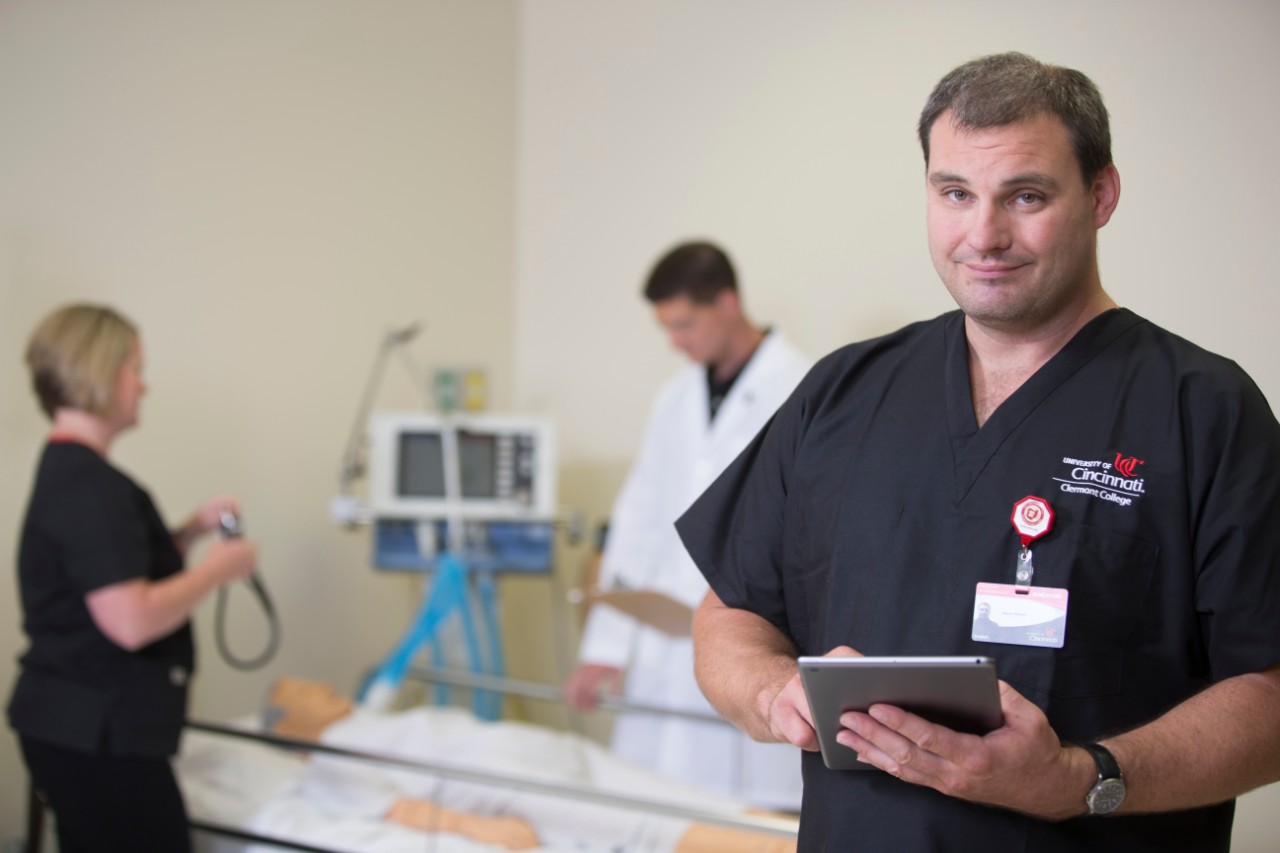 Student in scrubs poses for the camera in a hospital setting.