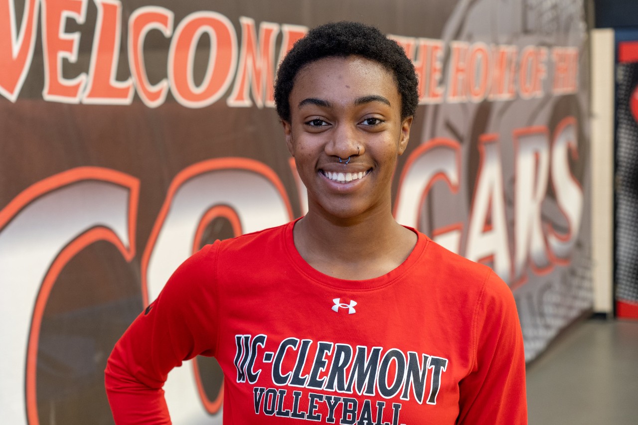 UC Clermont student and volleyball player Kayla Williams stands in front of a Clermont Cougars sign